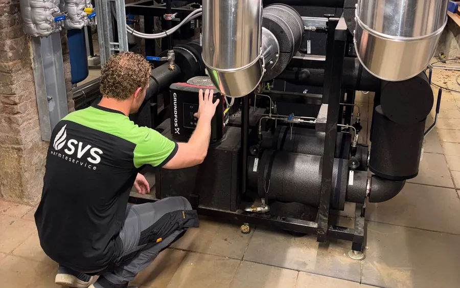 Monteur van SVS Warmteservice controleert de pomp van een warmteoverdrachtstation.