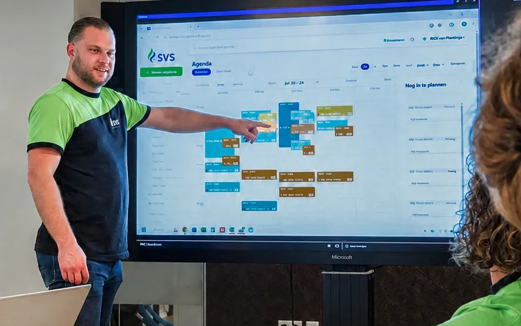 Collega van SVS licht de planning toe op het scherm in de overlegruimte.
