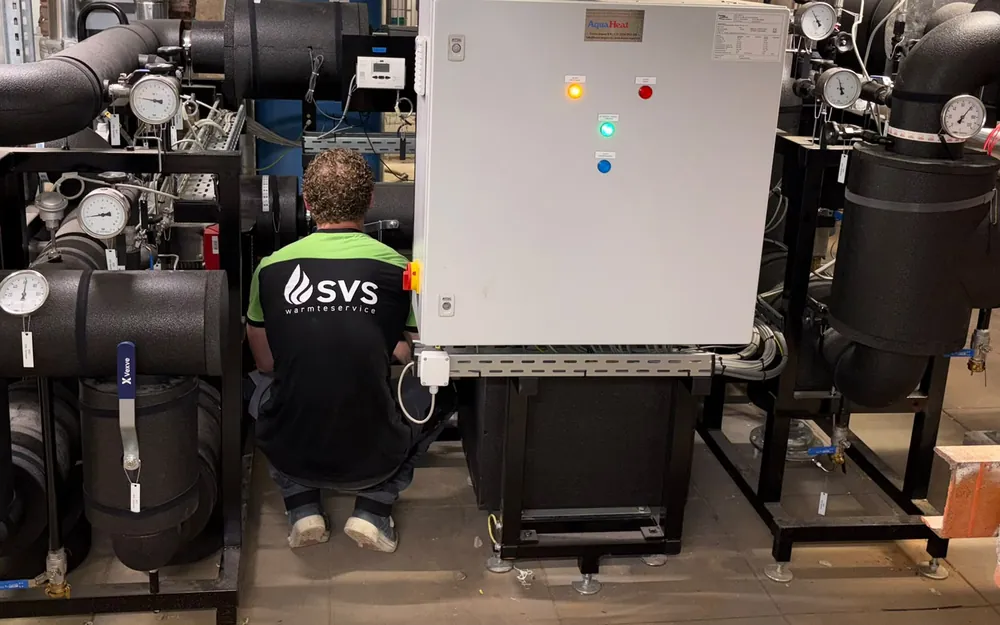 An SVS Warmteservice engineer working on the control panel of a district heating substation.
